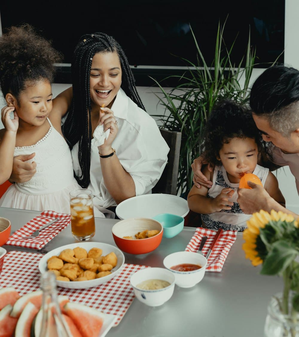 A family laughing and sharing food around the dinner table