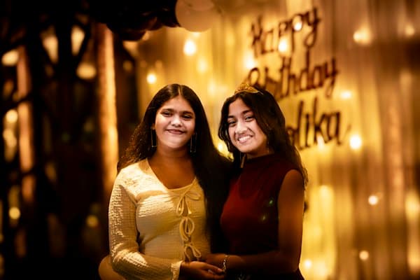 Two friends smiling in front of a birthday sign