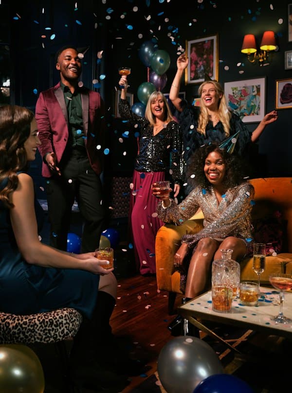 Friends celebrating under confetti and balloons