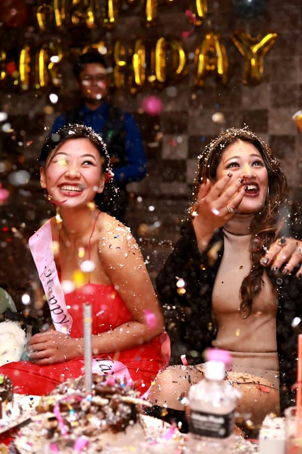 Two friends laughing as glitter falls