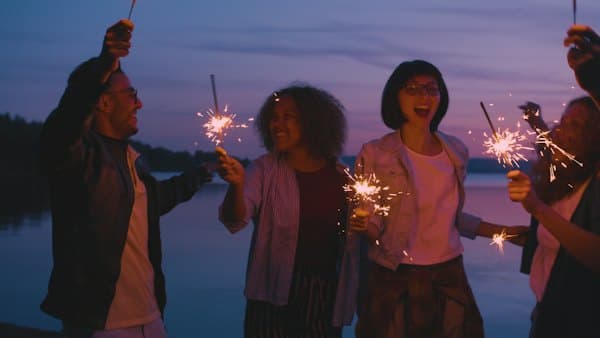 Friends holding sparklers at dusk